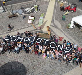 Une vue aérienne d'un groupe de personnes, tenant des lettres qui forment le mot "Compostons"