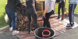 Voisins qui vident un bac d'apports pour transvaser le contenu dans un bac de maturation.